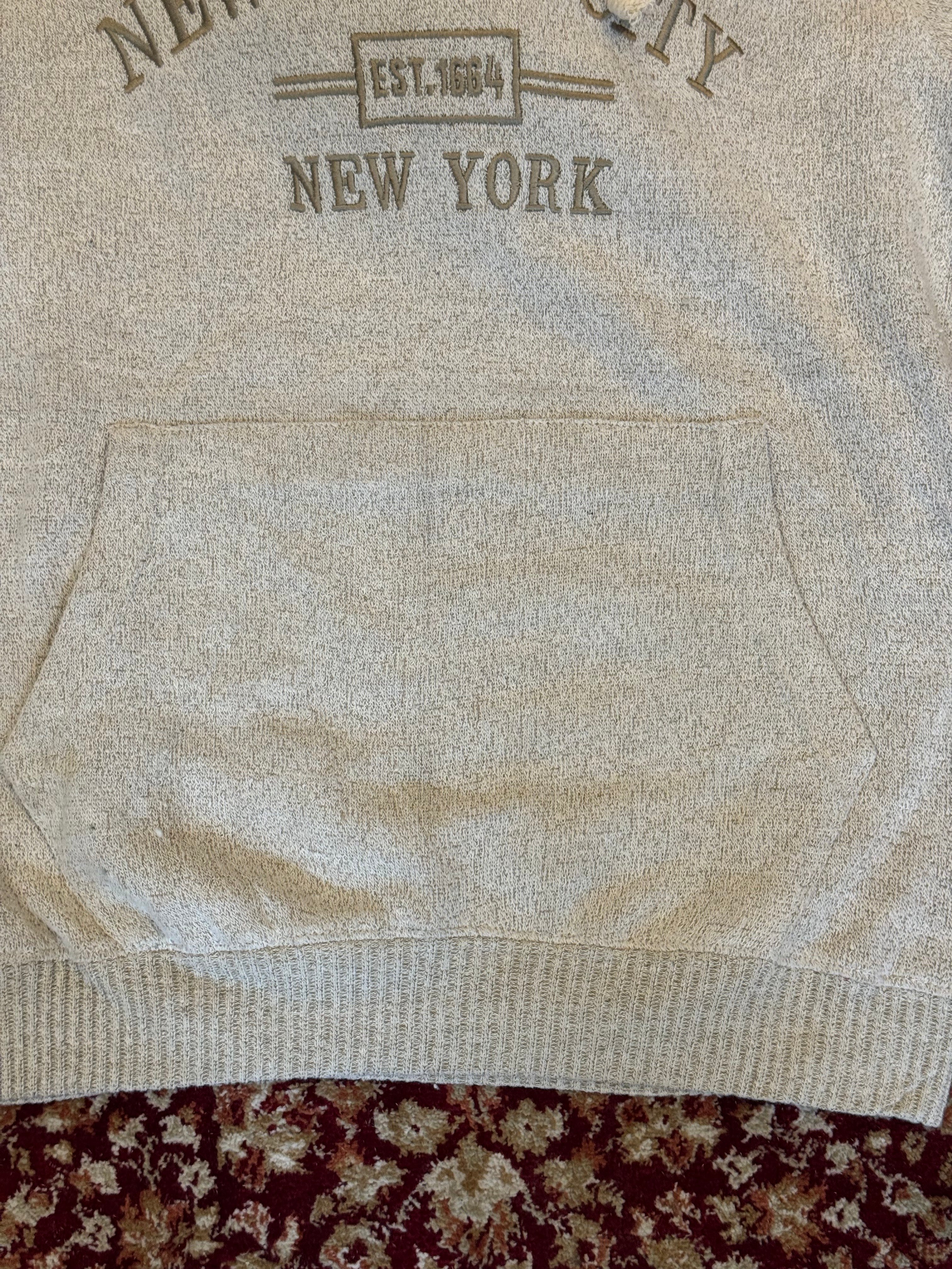 Close-up of a beige sweater with 'New York' text on a patterned fabric background